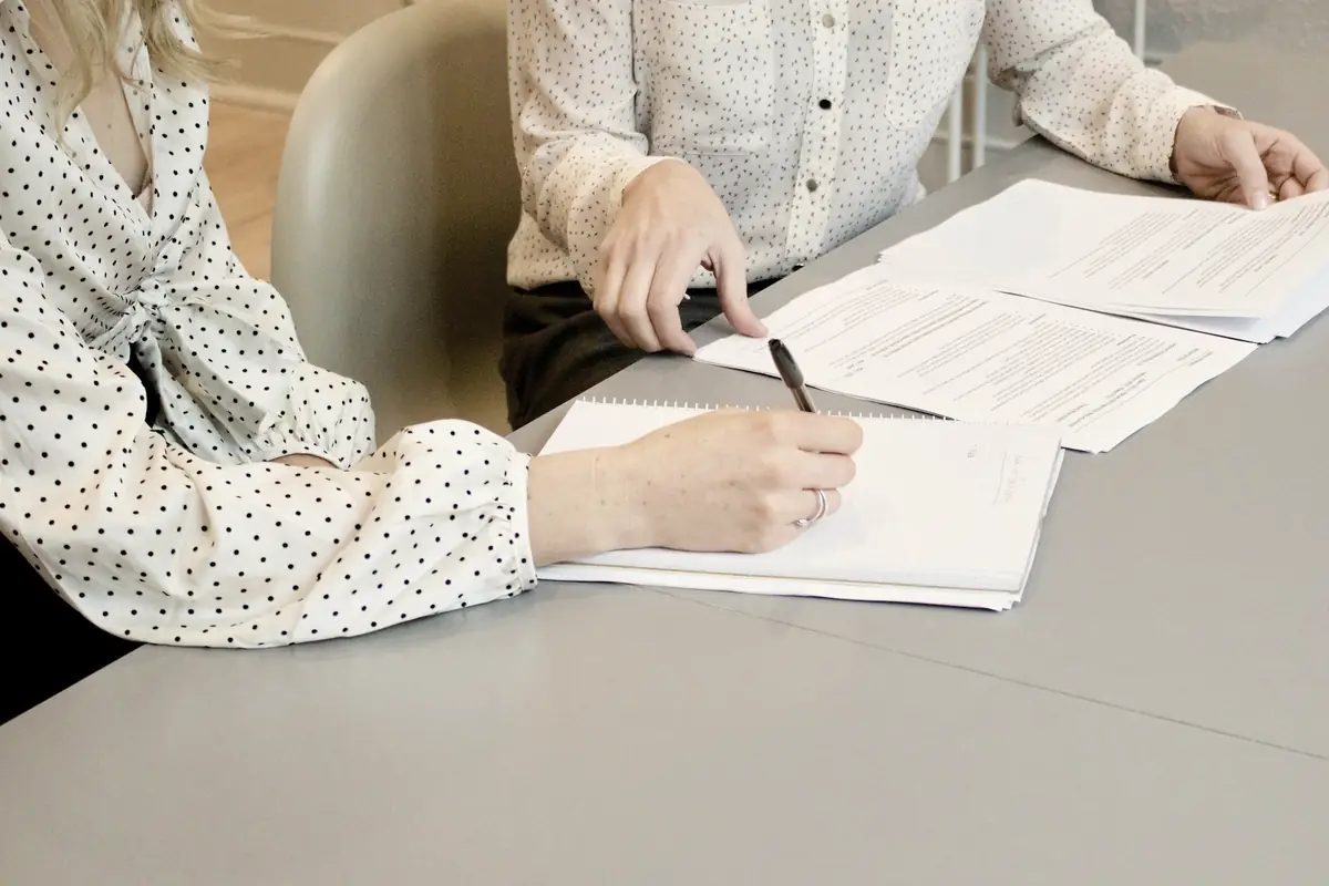 Dos personas firman un acuerdo por escrito sobre una mesa